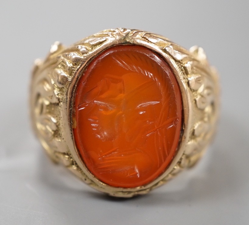 An early 20th century yellow metal and intaglio carnelian set signet ring, the matrix carved with the bust of a Roman soldier, with carved setting and shank, size M, gross weight 9.6 grams.